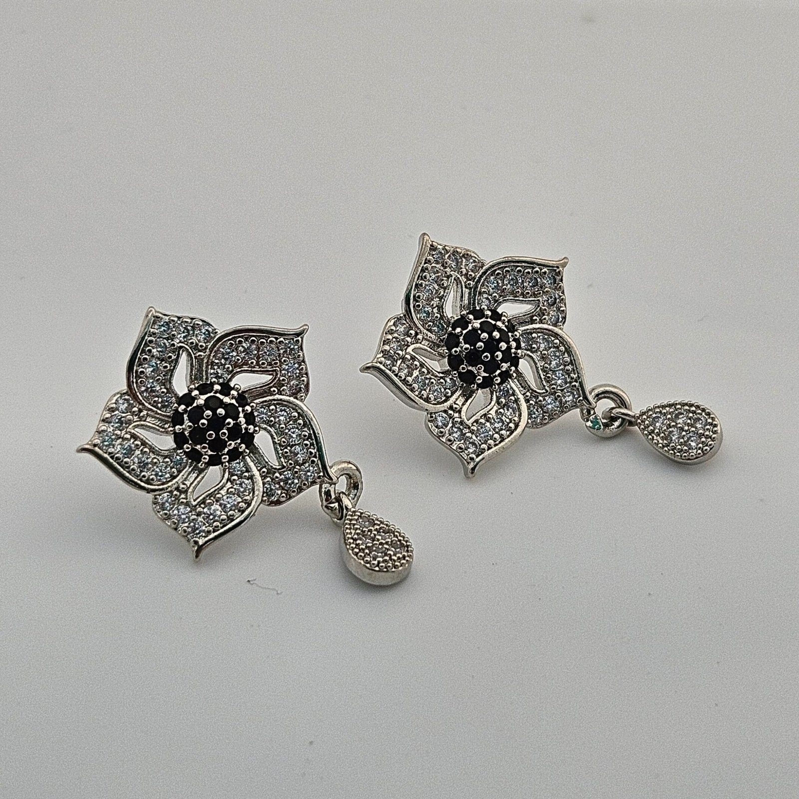 silver-toned, flower-shaped earrings with black and white accent stones